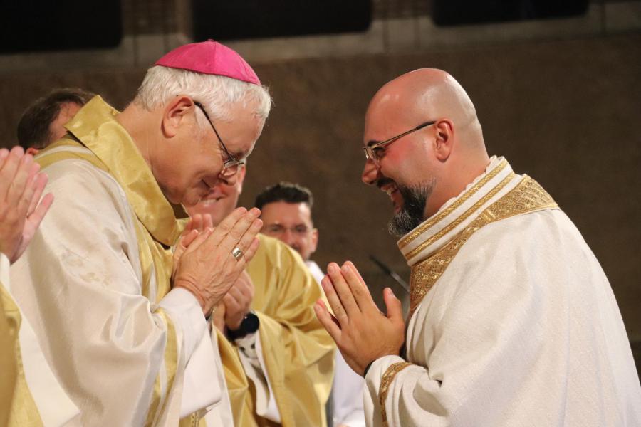 De bisschop en alle concelebranten wensen de vrede aan de nieuwe priester © Jente Vandewijer